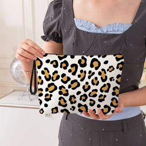 Leopard print makeup bag with handle held by model in a stylish home setting