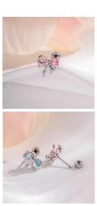 Macro shot of silver bow cartilage earrings with pink and blue drop-shaped crystals