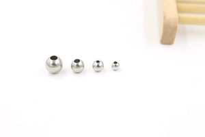 Detailed macro shot of four polished silver stainless steel spacer beads in various sizes