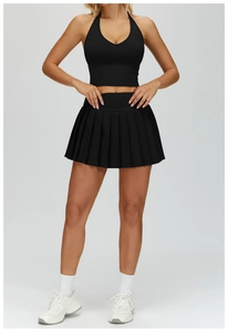 Detail of black pleated tennis skirt and halter crop top with matte performance fabric
