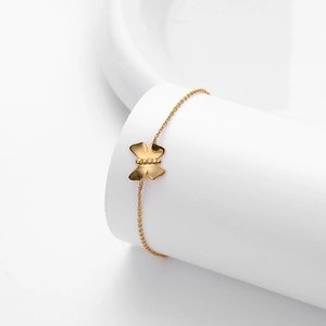 Polished gold S925 sterling silver butterfly bracelet on a minimalist white display stand