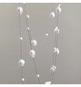 Close-up of irregular white pearls on a layered silver chain long sweater necklace