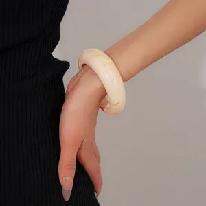 Minimalist wide resin bangle with amber marble texture worn on model wrist