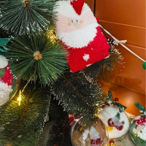 Plush Christmas socks featuring Santa Claus figures hanging on decorated pine branches