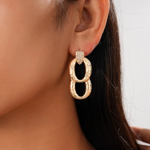 Close-up of vintage geometric gold oval earrings with zircon details on a model