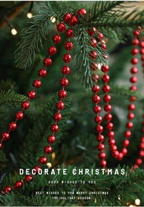 Close-up of shiny red bead garland draped on a Christmas tree with festive bokeh lights