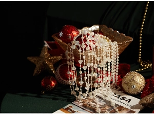 Detail of Christmas bead chain with white pearls and transparent crystals on a gold tray