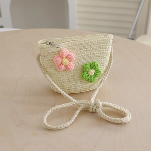 Detail of beige straw crossbody bag with crochet flower accents and zipper closure