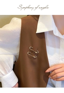 Detail of two gold metal star safety pins used as waist cinchers on dark clothing