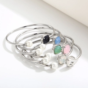 Dettaglio di bracciali a C in argento impilati con perle e pietre quadrate colorate