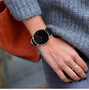 Close-up of minimalist black dial watch with rose gold indices and black leather strap
