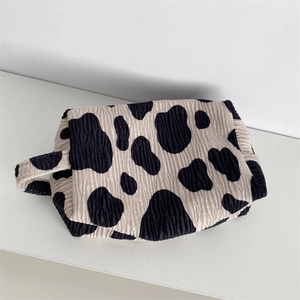 Macro detail of cow print velvet makeup bag with pleated texture and carry handle