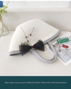 Close-up of woven cotton rope handbag featuring a black organza bow and gold bead accents