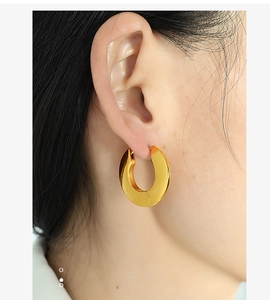 Close-up of a chunky minimalist gold-plated stainless steel hoop earring on a model