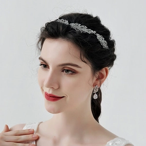 Detailed view of silver flower headband and teardrop rhinestone earrings on a model