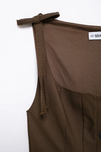 Detailed view of brown houndstooth vest with bow-knot shoulder straps and fabric texture