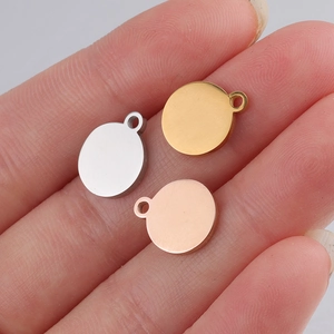 Close-up of three polished steel blank coin charms in silver, gold, and rose gold on fingertips