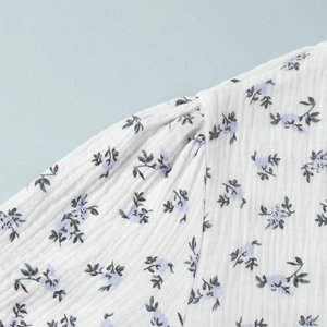 Detailed macro view of crinkle cotton fabric with blue floral print and pleated shoulder seam