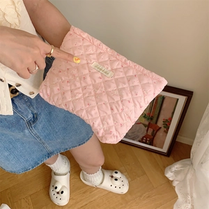Pink quilted fabric cosmetic bag with cute rabbit print held in a lifestyle setting