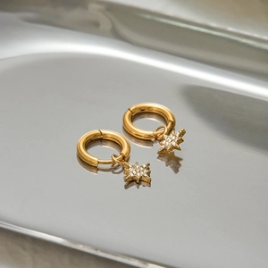 Close-up of gold star dangle earrings with pavé rhinestones on a metallic tray