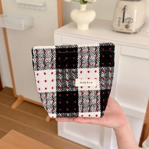 Close-up of vintage red and black plaid tweed fabric makeup bag with brand label