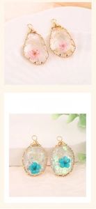 Detail of handmade resin oval pendants with real pink and blue dried flowers in gold wire