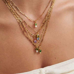 Collana dorata multistrato con zirconi colorati e ciondoli di perle su una modella
