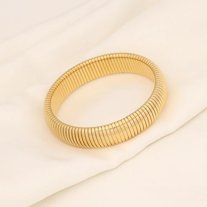 Macro shot of gold threaded elastic stretch bracelet on elegant beige fabric