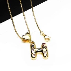 Close-up of gold letter H pendant with colorful zircon stones and small heart charm