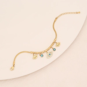 Detail of gold snake chain with turquoise beads and evil eye charms with crystals