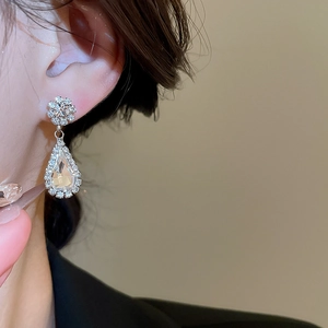 Close-up of sparkling waterdrop and flower diamond earring worn by a female model