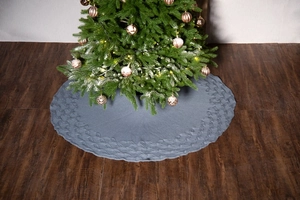 Detailed macro shot of gray knitted Christmas tree skirt with cable knit pattern on wood floor