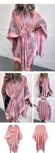 Detailed view of pink blend knit poncho featuring decorative pom poms and tassel hem