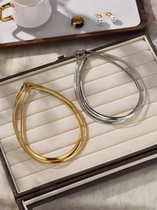 Flat lay of minimalist gold and silver snake chain necklaces in a velvet jewelry box
