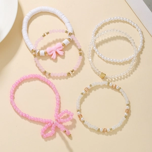 Detail of pink and white boho beaded bracelets with bow and heart charms for women