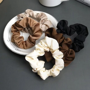 Set di 5 elastici per capelli in raso beige e marrone su uno sfondo minimalista