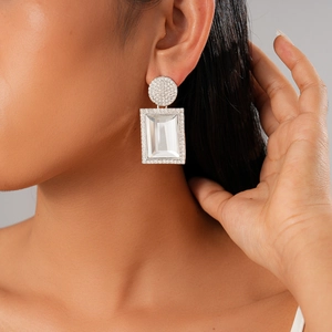 Dettaglio dell'orecchino geometrico color argento con pavé di cristalli trasparenti