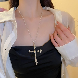 Primo piano della collana con ciondolo a croce barocca vintage e perle su una modella