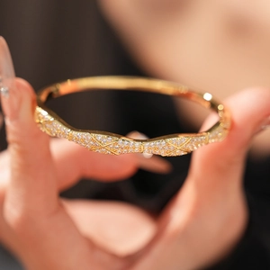 Macro detail of gold plated bangle with sparkling cubic zirconia and quilted cross pattern