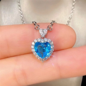 Macro shot of silver heart necklace with blue topaz gemstone and clear crystal border