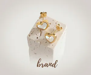 Close-up of heart-shaped gold earrings with white shell inlay on stone display