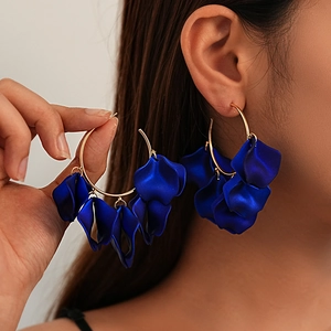 Detailed close-up of blue acrylic petal earrings with large gold-tone hoops on model