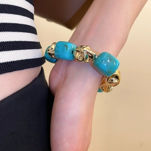 Detailed shot of chunky turquoise beaded bracelet with gold accents on model's wrist