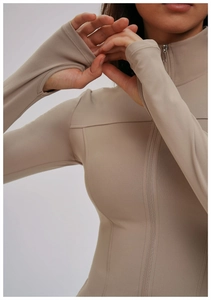 Detailaufnahme der sandfarbenen Yoga-Jacke mit Daumenlöchern und Metallreißverschluss