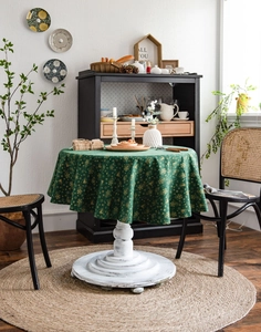 Detail of dark green round tablecloth with golden Christmas bells and snowflakes