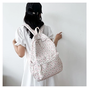 Rear view of floral canvas backpack on model featuring pink floral print and side pockets