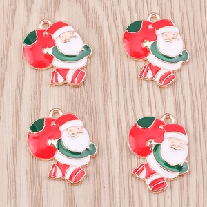 Detail of red and white enamel Santa Claus alloy pendants with gold-plated edges on wood