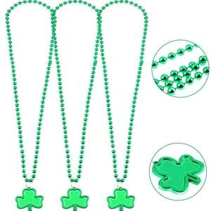 Detailed view of green St. Patrick's Day bead necklaces with clover pendants on white background