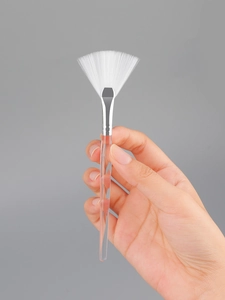 Detail of fan brush with white synthetic bristles and a sleek transparent handle