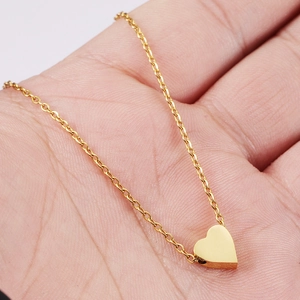 Collana con ciondolo a cuore d'oro lucido su catena minimalista tenuta in mano